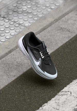 Mustmustelased spordijalatsid tekstureeritud pealmise, valgete detailide ja pehme tallaga. Disain sisaldab logo ja kerget konstruktsiooni.