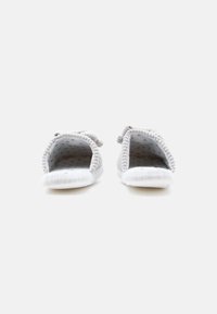 Un par de zapatillas tejidas grises con suelas blancas, mostradas de frente sobre un fondo blanco.