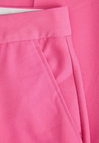 Roze tkanina s glatkom teksturom, koja ima pojas i bočnu džep. Materijal izgleda mekano i blago elastično.