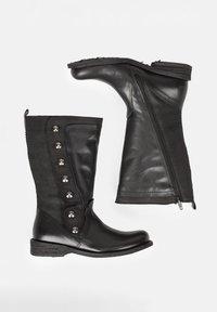 Botas negras que combinan cuero liso y ante, con punta redondeada, botones decorativos plateados y una cremallera lateral.
