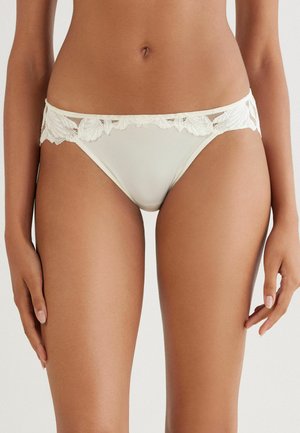 Damen-Bikiniunterwäsche aus Creme mit Spitzenbesatz, ausgestattet mit einer glatten Vorderseite und floralen Spitzen details am Bund, die einen zarten Eindruck vermittelt.