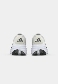 Zwart-witte hardloopschoenen met een gestructureerde bovenkant, gevoerde kraag en kenmerkend drie-strepenlogo op de hiel; flexibele rubberen loopzool.