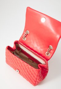 Rode gewatteerde handtas met een gladde leren klep, gouden hardware accenten, een kettingdetail en een interne ritszak. Gedecoreerde voering.