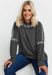 Mörkgrå långärmad tröja med ribbat mönster, accentuerad med nitar längs axlarna och halsringningen.