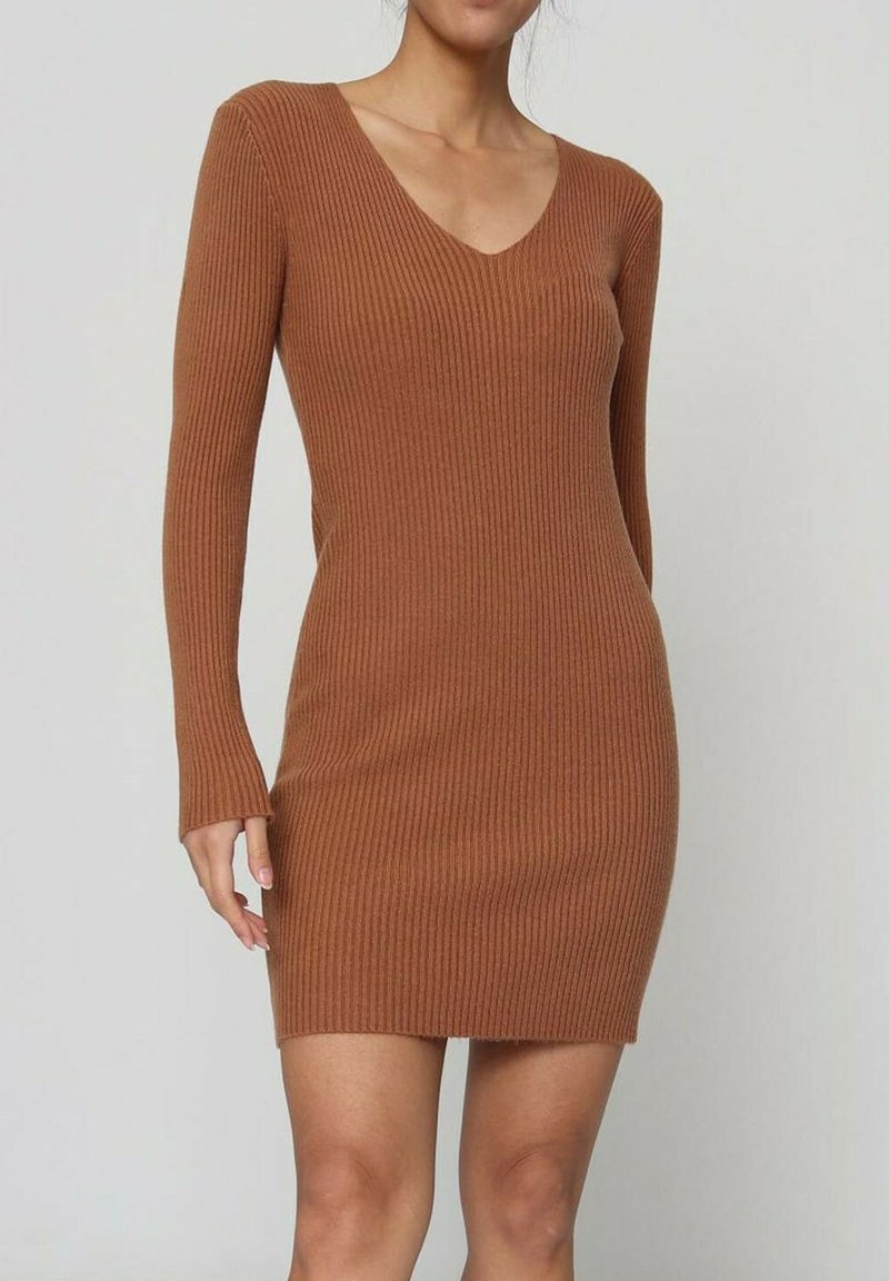 Robe côtelée couleur rouille avec manches longues et décolleté en V. Texture douce, coupe près du corps, se terminant au-dessus de mi-cuisse. Motif vertical subtil.