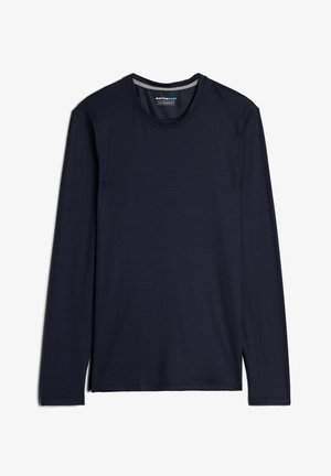 Mørkeblå langærmet skjorte lavet af merinould, med rund halsudskæring og en glat tekstur, der har slidser i siden ved kanten og et vævet mærke.