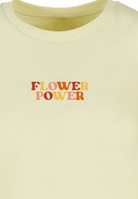 Light yellow sweatshirt featuring a "FLOWER POWER" graphic in multicolored text. Ribbed neckline and soft fabric with a smooth texture.
