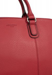 Borsa a tracolla rossa in pelle con finitura testurizzata, dotata di un accessorio in metallo argentato e dettagli cuciti. Logo visibile con la scritta "HEXAGONA PARIS."