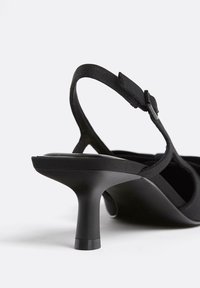 Czarna sandał na wysokim obcasie z gładkim paskiem i regulowanym zapięciem. Posiada zaokrąglony nosek oraz rozszerzający się design obcasa.