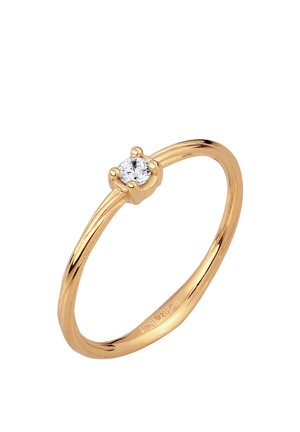 Bague fine en or avec une petite pierre précieuse ronde et claire sertie de quatre griffes sur un fond blanc.