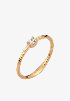 Tynd guldring med en lille rund klar ædelsten sænket i en fire-klo indfatning på en hvid baggrund.