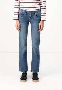 Blue denim jeans with a straight leg design, featuring front pockets and a button closure. Worn with black sneakers.