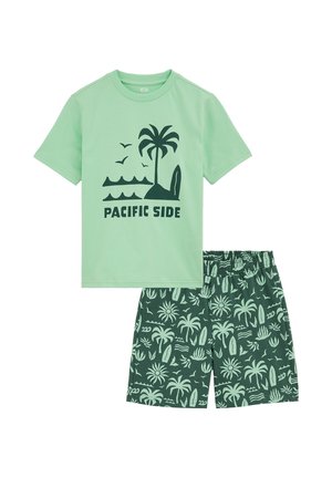 Zelené bavlnené tričko s čiernym nápisom "PACIFIC SIDE" a grafikou palmy; zodpovedajúce šortky so zeleným tropickým vzorom a elastickým pásom.