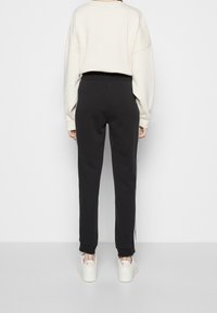 Svarta joggare med smal passform, med vita sidostråk, tillsammans med en crème-färgad oversized sweatshirt och plattformssneakers.