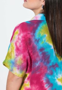 Maglietta tie-dye multicolore con motivi vivaci in rosa, blu, verde e giallo. Tessuto morbido con una vestibilità rilassata e maniche corte.