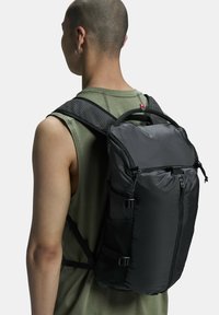 Black backpack made of durable fabric, featuring a zippered front, side pockets, and padded shoulder straps for comfort and support.