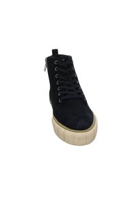 Basket montante noire avec semelle épaisse beige, lacets noirs et fermeture éclair à l'arrière sur fond blanc.