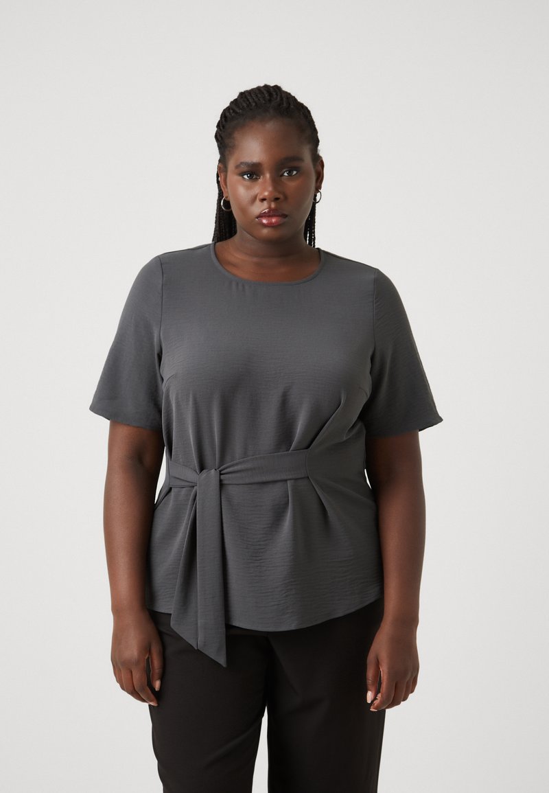 Gray short-sleeve top with a ribbed texture, a round neckline, and a tied waist detail. Paired with black trousers.