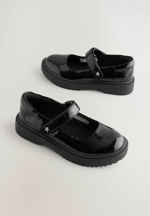 Scarpe Mary Jane in pelle verniciata nera con cinturino in velcro e accentuazione a stella, dotate di una spessa suola in gomma e design a punta arrotondata.