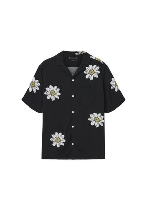 Zwart shirt met korte mouwen, versierd met witte en gele bloemrijke borduursels, voorzien van een zak en knoopsluiting aan de voorkant. Gladde stoftextuur.