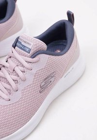 Scarpe da ginnastica sportive in rete di colore rosa chiaro con tessuto testurizzato, lacci tonali e un accento blu scuro sul collo. Presentano una suola bianca e un dettaglio con il logo.