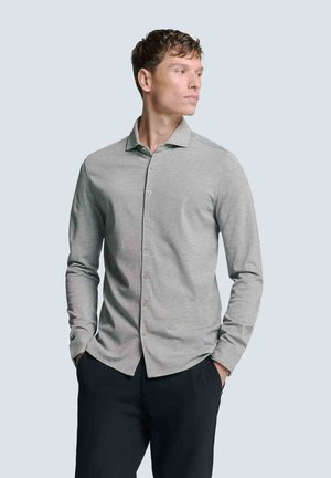 Lichtgrijze langarm blouse met knopen en een kraag, met een gladde textuur en minimalistisch ontwerp, gecombineerd met donkere broeken.