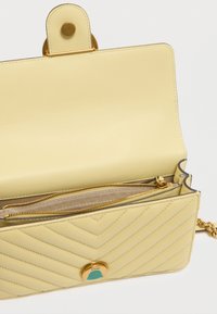 Κίτρινη δερμάτινη τσάντα χειρός με σχέδιο σε λαχνό, χρυσά μεταλλικά στοιχεία και τυρκουάζ λεπτομέρεια. Περιλαμβάνει εσωτερική τσέπη με φερμουάρ και λουρί αλυσίδα.