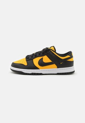 Zapatillas Nike Dunk en negro y amarillo con parte superior de cuero, puntera perforada y media suela blanca; incluye cordones y acentos de logotipo.