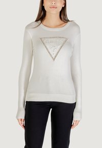 Suéter de punto de manga larga blanco con un logo triangular de "GUESS" adornado con rhinestones, puños acanalados y una silueta ajustada.