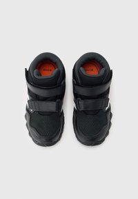 Mustad laste tossud, millel on takjapaelad, võrgukangast pealsed ja oranžid sisetallad, ühel valgel taustal.