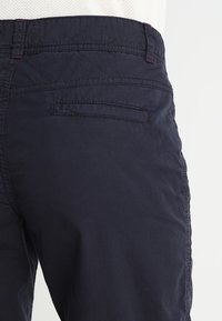 Pantaloni blu navy realizzati in tessuto morbido, con una vestibilità slim, tasche laterali e posteriori, e dettagli di cucitura a contrasto.