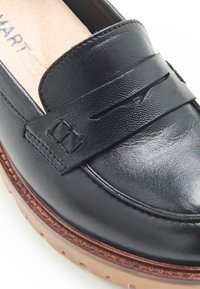 Mocassino in pelle nera con finitura texturizzata, dotato di una fascia sulla parte anteriore e suola in gomma con bordo decorato.