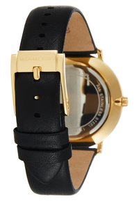 Black leather watch strap with gold-tone stainless steel case. Adjustable buckle and textured finish. Transparent back reveals mechanism.