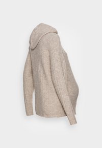 Beżowy, żeberkowy sweter ciążowy z długimi rękawami i luźnym krojem, który pomieści brzuszek ciążowy, przedstawiony z boku.