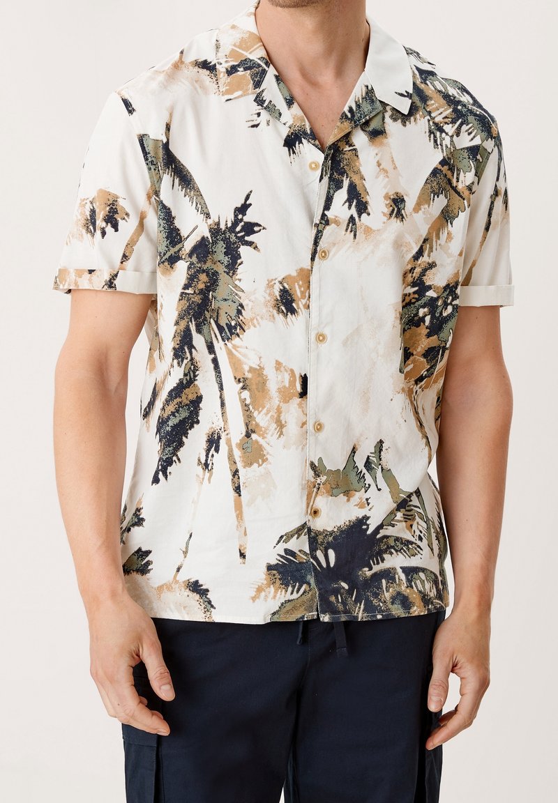 Camicia a maniche corte con bottoni di colore bianco, decorata con un motivo a foglie di palma nei toni del verde, marrone e blu scuro. Presenta una texture morbida e una vestibilità rilassata.