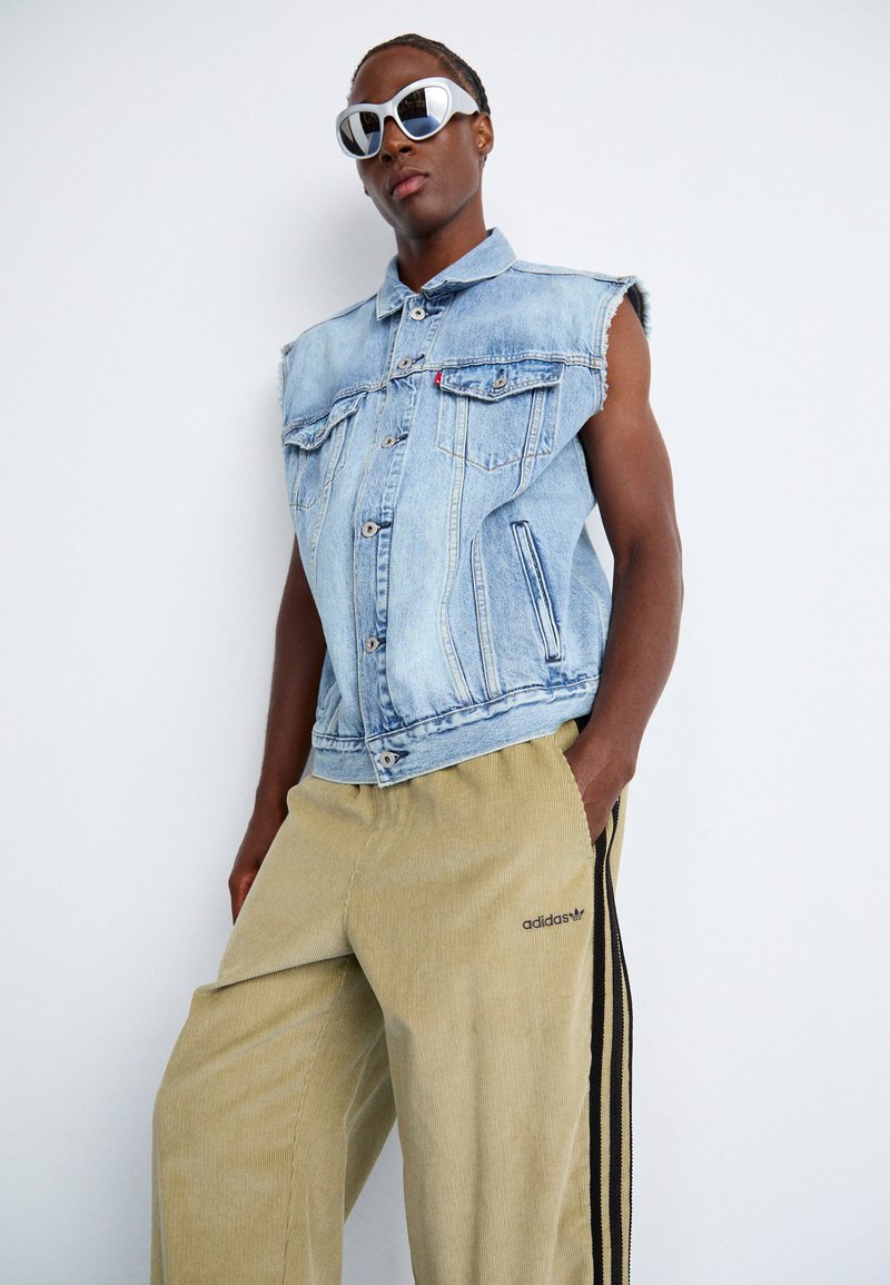 Lysblå denimvest med ærmeløst design, med brystlommer og frynsede kanter. Matchet med tanfarvede kordfløjlshorts med sorte striber.