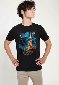 Černé bavlněné tričko s barevným motivem Star Wars, zobrazující postavy a hvězdné pozadí s tučným textem ve spodní části.