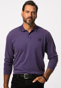 Paars polo shirt met lange mouwen en een zwarte kraagdetail en klein logo. Draagt met zwarte broek en een gestructureerde zwarte riem.