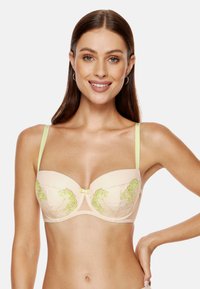 Beżowy stanik z poduszkami, z delikatnym zielonym haftem w kwiaty, przezroczystymi akcentami i jasnymi zielonymi ramiączkami. Posiada mały detal w postaci kokardy na środku.