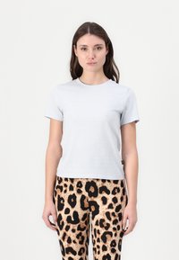 Ανοιχτό γκρίζο, κοντομάνικο μπλουζάκι κατασκευασμένο από λεία ύφανση. Φοριέται με παντελόνια με σχέδιο που διαθέτει καφέ και μαύρο λεοπάρδαλη.