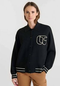 Cardigan nero con scollo a collo, chiusura frontale con bottoni, dettagli a righe bianche sulle maniche e logo ricamato sul petto.