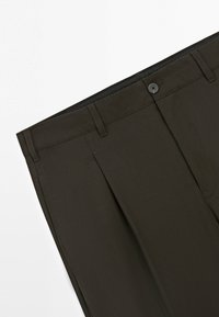 Ciemnooliwkowe spodnie do garnituru z szlufkami na pasek, zapięciem na guziki i plisowaniem na przodzie, na białym tle.