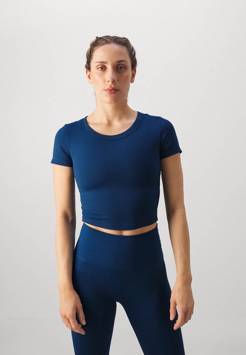 Marineblauw cropped T-shirt met korte mouwen en een ronde halslijn, gemaakt van zacht, rekbaar materiaal, gecombineerd met high-waisted leggings in dezelfde kleur.