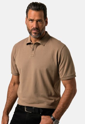 Polo de manga corta en color marrón claro, hecho de algodón texturizado. Presenta una tapeta de botones, cuello acanalado, y se combina con pantalones negros y un cinturón.