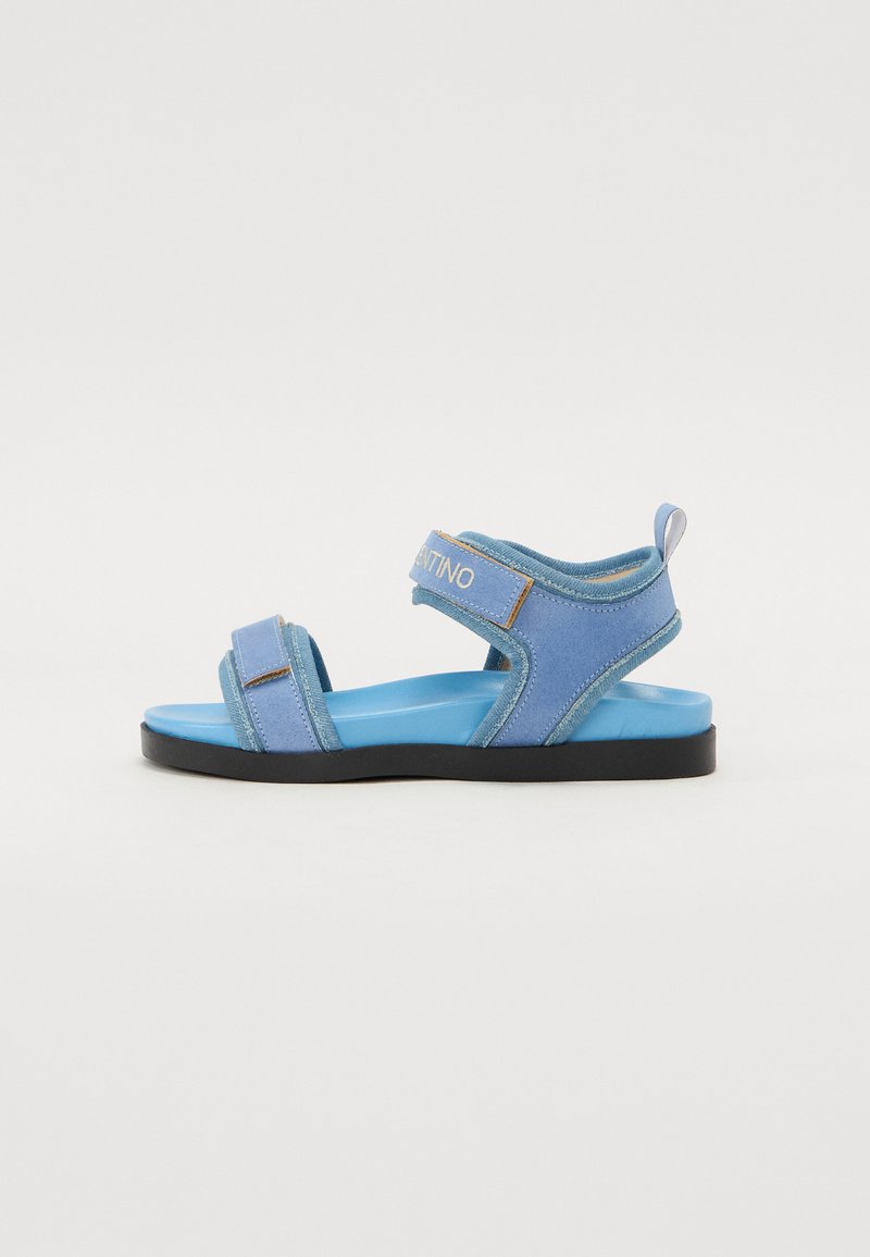 Siniset sandaalit pehmeällä päällisellä, säädettävillä remmeillä ja pehmustetulla pohjalla. Ominaisuuksiin kuuluu kontrastoiva tumma pohja ja brändäys remmissä.