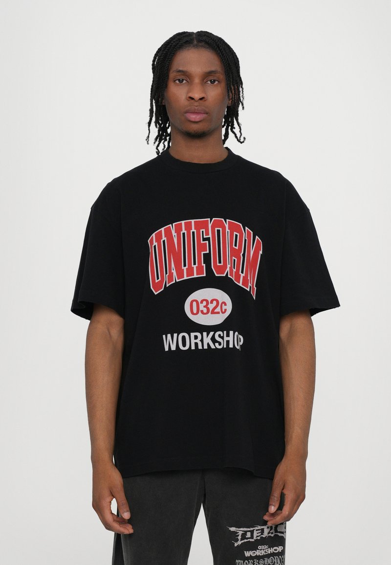 Sorte oversized t-shirt med iøjnefaldende rødt "UNIFORM" tekst, hvid cirkulær grafik med "032c," og "WORKSHOP" i gråt på forsiden.