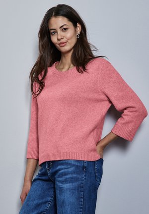 Maglione in lana rosa chiaro con scollo rotondo e maniche a tre quarti, abbinato a jeans in denim blu. Tessuto morbido e dettagli a coste sul bordo.
