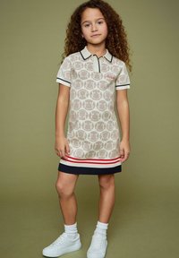 Beige polo-stiilis kleit, millel on ringikujuline mustriline, must äär, punased ja valged horisontaalsed triibud hemil ning kombineeritud valgete tossudega.