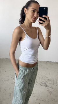 Top sin mangas blanco combinado con pantalones sueltos de rayas verdes y blancas. Tela suave con una forma ajustada y cinturilla relajada.