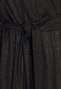 Černá texturovaná tkanina s vertikálními sklady a jemným metalickým leskem. Obsahuje detail vázaného pásku s nařasenými sekcemi.